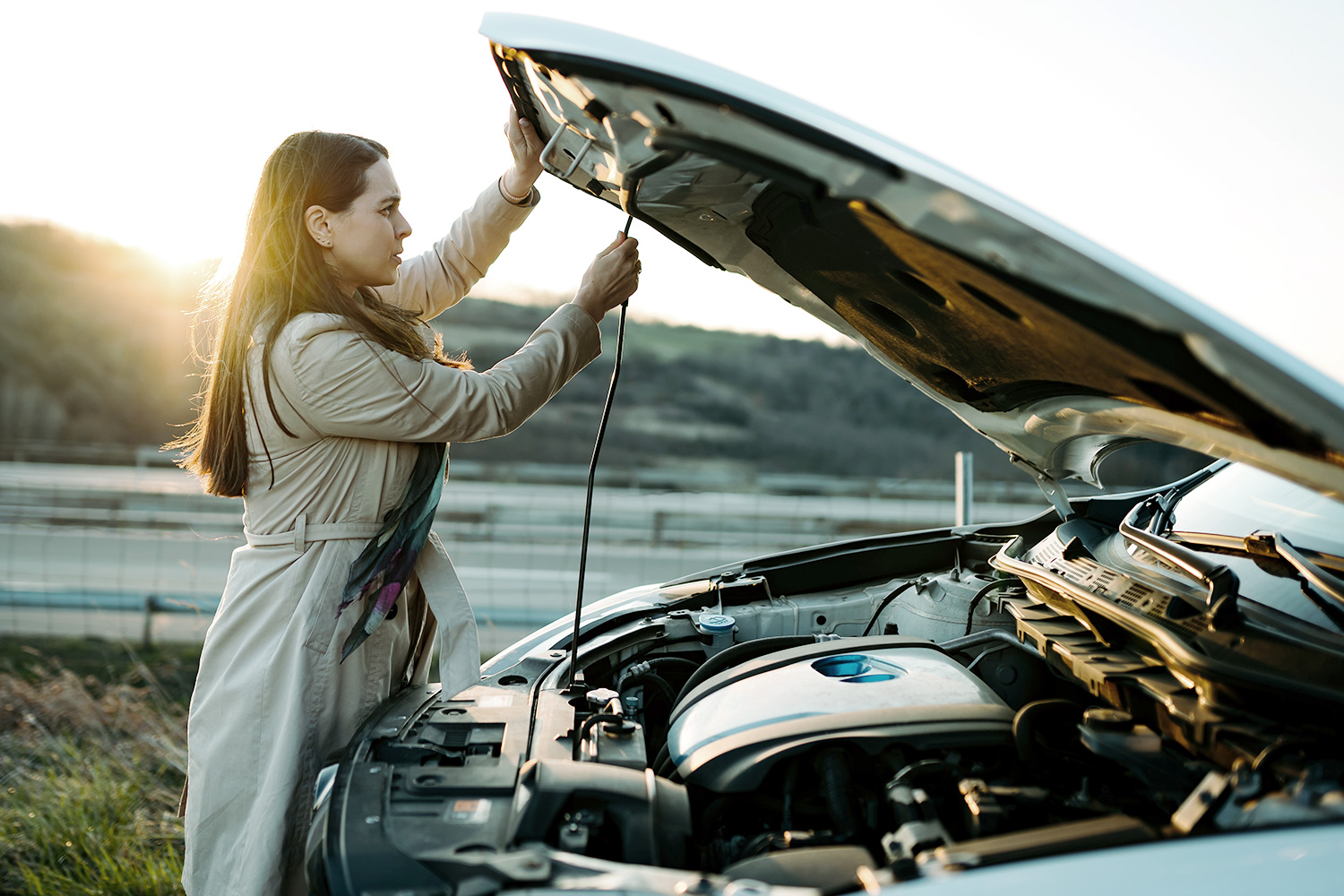 Mujer revisando el motor de su auto que tiene seguro vehicular