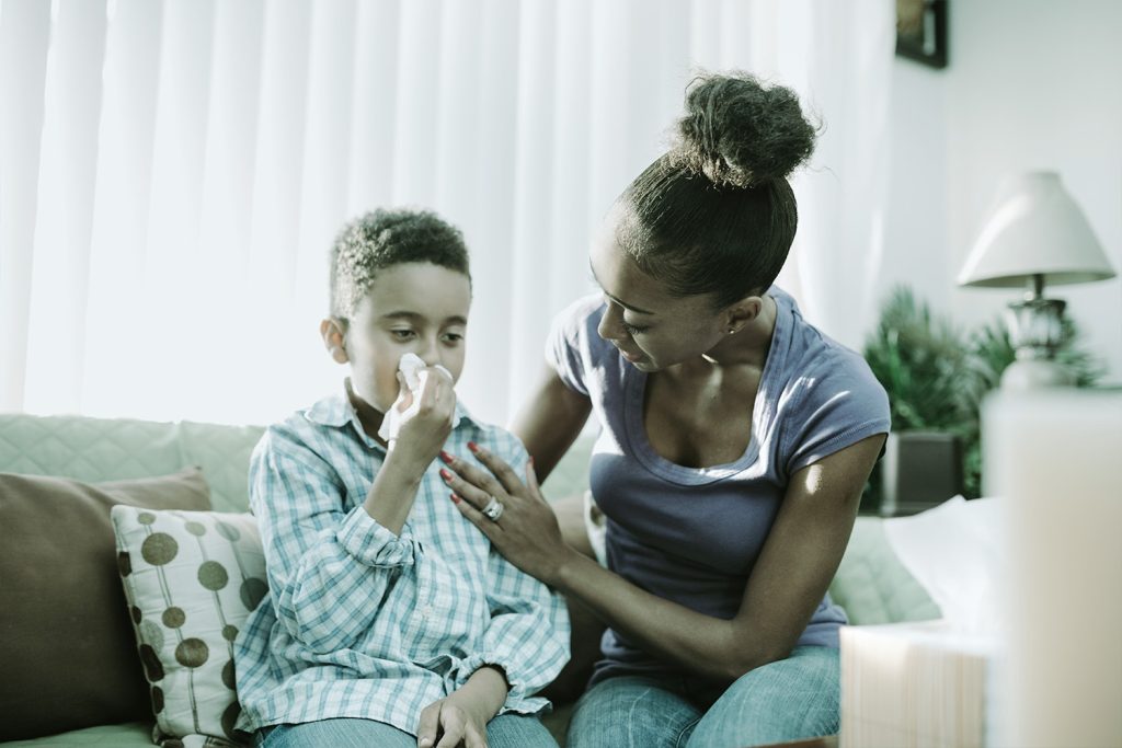 Niño enfermo con tos ferina mientras mamá lo cuida.