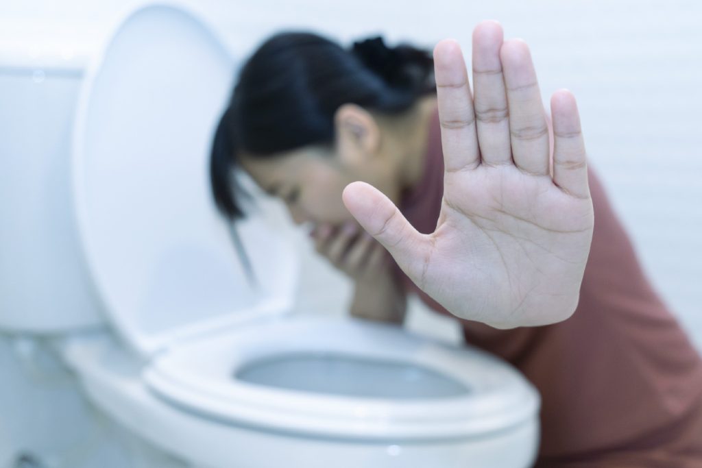 Mujer con infección estomacal vomitando.