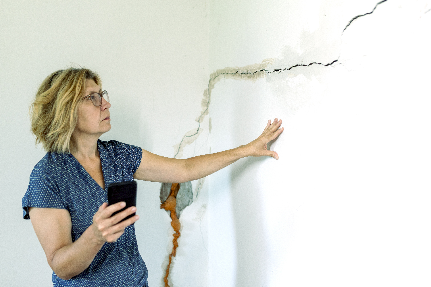 En la imagen vemos a una persona preocupada porque un temblor afectó su casa y no cuenta con un seguro de hogar.