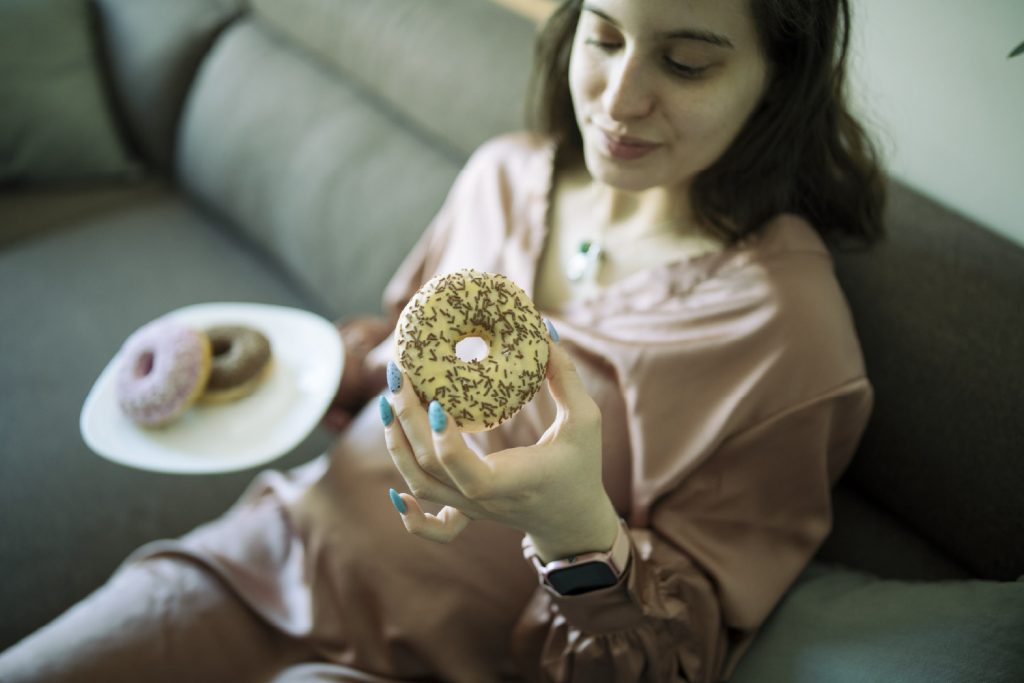 Mujer comiendo donuts presenta síntomas diabetes