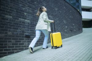 Mujer corriendo con maleta asegurada con seguro de viaje